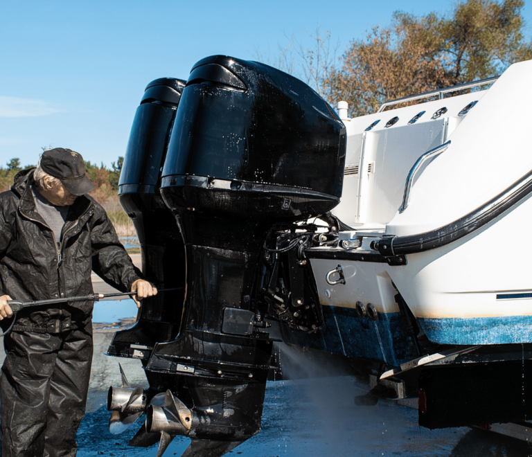 Mann reinigt Boot mit Wasserschlauch